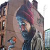 Grote muurschildering van Smug met roodborstje op de muur van een gebouw in Glasgow